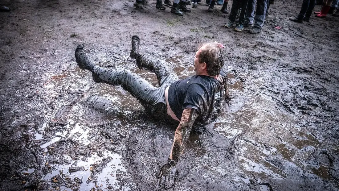 Festivalgast im Schlamm, umringt vom Publikum bei Holtebüttel Rockt 2025