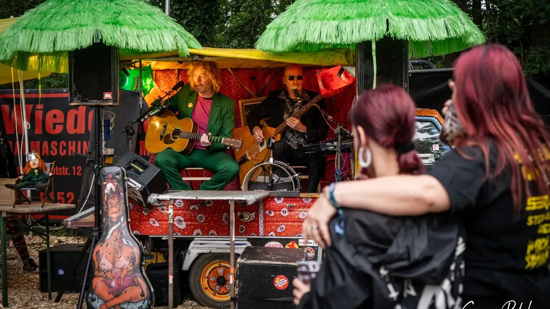 Festivalgäste vor einem Getränkestand mit grünen Schirmen, Holtebüttel Rockt 2024